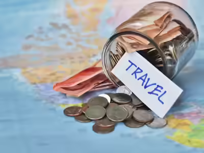 budget travel destination a glass full of coins and a note of travel on world map